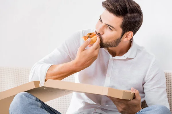 Porträt eines jungen Mannes, der allein zu Hause Pizza isst — Stockfoto