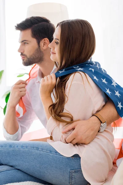 Side view of young couple covered with american flag at home — Stock Photo