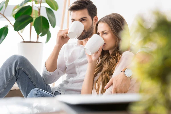 Retrato jovem casal amoroso beber café no sofá em casa — Fotografia de Stock