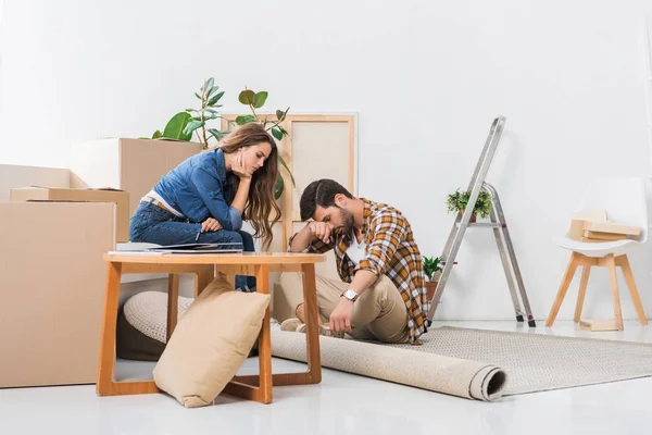 Pareja joven y cansada en casa nueva con cajas de cartón, concepto de casa móvil - foto de stock