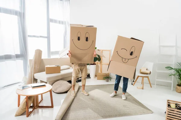 Vista oscurecida de pareja con cajas de cartón en cabezas en casa nueva, concepto de casa móvil - foto de stock