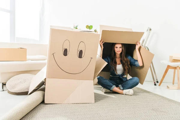 Молода жінка з картонними коробками сидить на підлозі в новому будинку — стокове фото