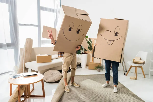 Vue obscurcie du couple avec des boîtes en carton sur les têtes à la nouvelle maison, déménagement concept de maison — Photo de stock