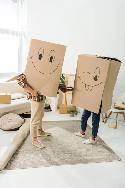 Obscured view of couple with cardboard boxes on heads holding hands at new house, moving home concept — Stock Photo