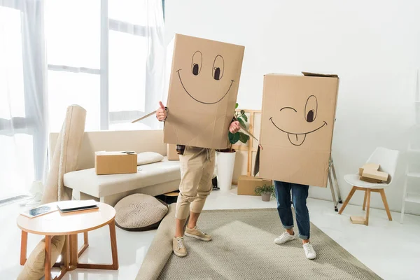 Vista oscurecida de pareja con cajas de cartón en cabezas en casa nueva, concepto de casa móvil - foto de stock