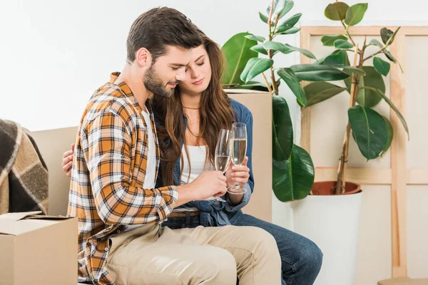 Couple in love with glasses of champagne at new house with cardboard boxes, moving home concept — Stock Photo