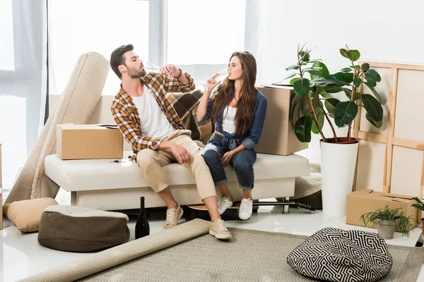 Verliebtes Paar trinkt Champagner im neuen Haus mit Pappkartons, Umzugskonzept — Stockfoto