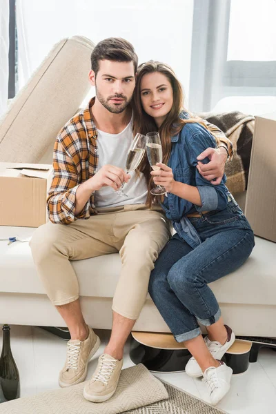 Verliebtes Paar klappert Sektgläser im neuen Haus mit Pappkartons, Umzugskonzept — Stockfoto