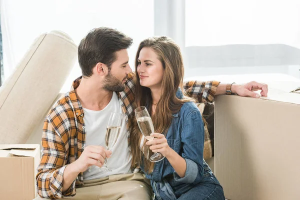 Ritratto di coppia innamorata che tintinna bicchieri di champagne nella nuova casa con scatole di cartone, concetto di casa mobile — Foto stock