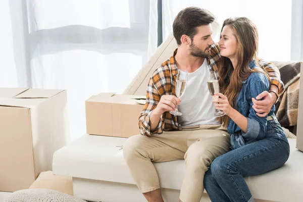 Casal apaixonado por copos de champanhe na nova casa com caixas de papelão, movendo-se para casa conceito — Fotografia de Stock