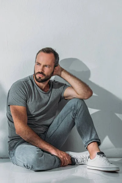 Full length view of depressed bearded middle aged man sitting and looking away — Stock Photo