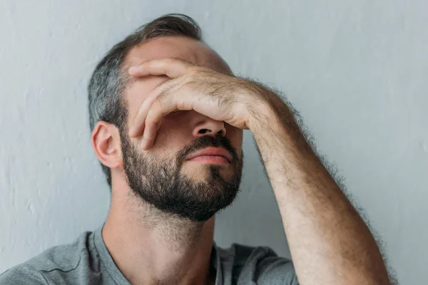 Close-up view of bearded frustrated mid adult man with hand on face — Stock Photo
