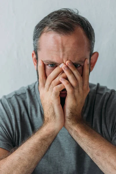 Dépressif barbu homme d'âge moyen tenant la main sur le visage et regardant la caméra — Photo de stock