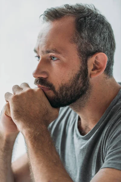 Primer plano vista de triste guapo barbudo hombre cogido de la mano en la barbilla y mirando hacia otro lado - foto de stock