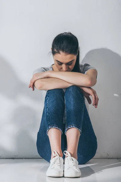 Full length view of sad stressed girl sitting with hands on knees on floor — Stock Photo