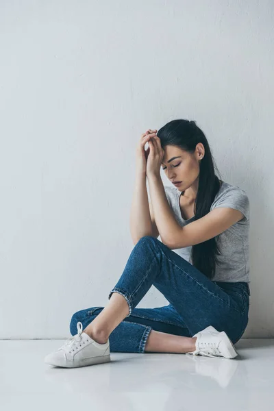 Вид в полный рост грустной депрессивной молодой женщины, сидящей на полу — стоковое фото