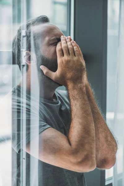 Visão lateral de deprimido homem barbudo frustrado chorando com as mãos no rosto — Fotografia de Stock