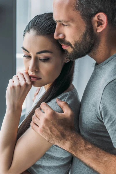 Side view of bearded man embracing and supporting upset young woman — Stock Photo