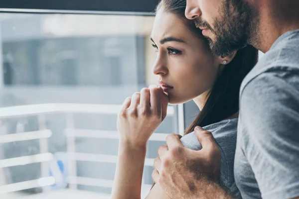 Plan recadré de barbu homme soutien triste jeune femme regardant fenêtre — Photo de stock