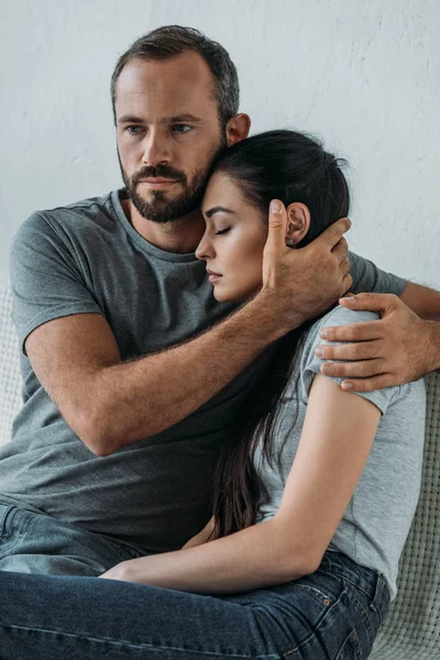 Barbudo hombre apoyo y abrazo estresado triste mujer sentado en sofá - foto de stock