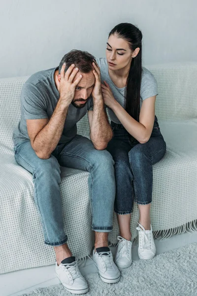 Vista ad alto angolo di giovane donna che sostiene fidanzato stressato seduto sul divano — Foto stock