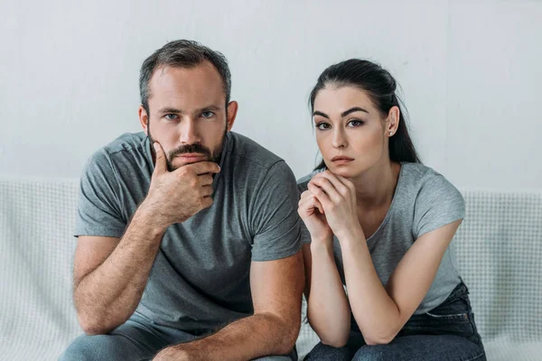 Couple triste assis sur le canapé et regardant la caméra, concept de difficultés relationnelles — Photo de stock