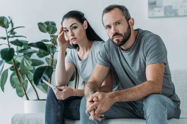 Triste casal estressado com teste de gravidez sentado e olhando para a câmera — Fotografia de Stock