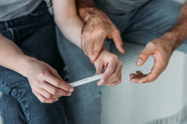 Tiro recortado de casal infeliz segurando teste de gravidez — Fotografia de Stock