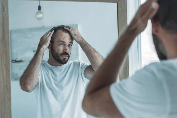 Обрезанный снимок мужчины средних лет с облысением, смотрящего на зеркало, концепция выпадения волос — стоковое фото
