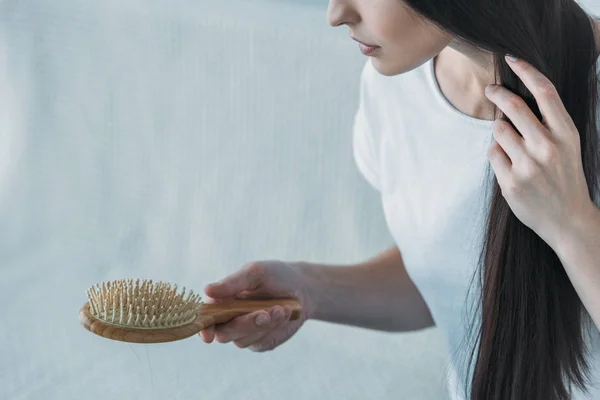 Colpo ritagliato di triste bruna donna che tiene la spazzola per capelli, concetto di perdita di capelli — Foto stock