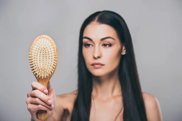 Aufgebracht brünette Frau mit Haarbürste isoliert auf grau, Haarausfall Konzept — Stockfoto
