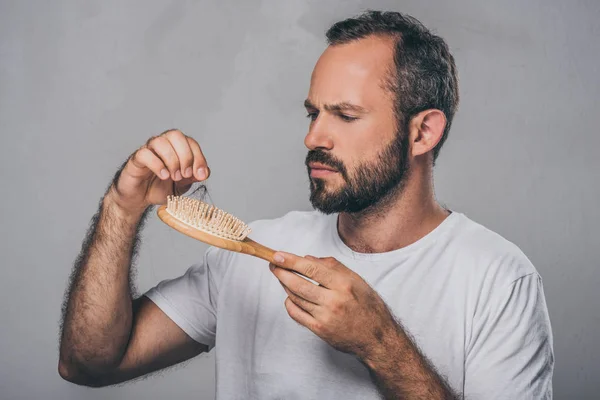 Barbuto uomo di mezza età in possesso di spazzola per capelli, concetto di perdita di capelli — Foto stock