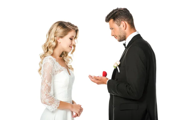Vista lateral del novio mostrando anillos de boda a la novia aislada en blanco - foto de stock