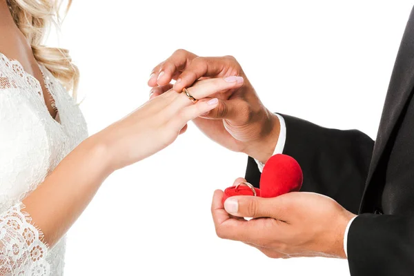 Обрізаний знімок нареченого, що надягає обручку на палець наречених ізольовано на білому — стокове фото