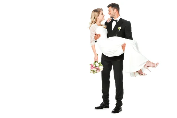 Feliz jovem noivo carregando sua noiva isolada no branco — Fotografia de Stock