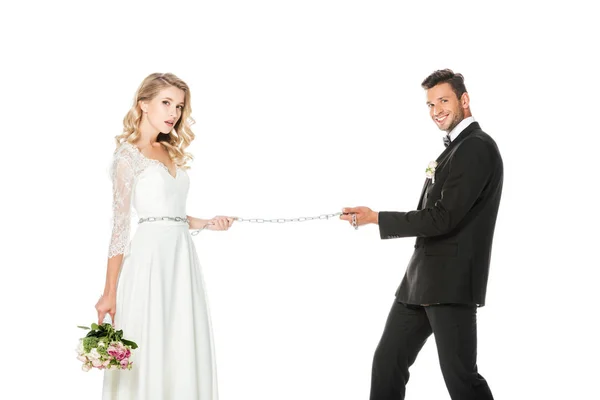 Glücklicher junger Bräutigam mit Kette und angeleinter Braut isoliert auf weiß — Stockfoto