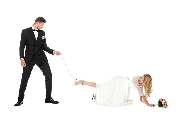 Красивий наречений тримає ланцюг пов'язаний навколо ноги наречених ізольовано на білому — стокове фото