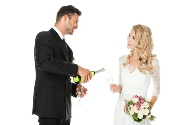 Groom pouring champagne while bride holding glass isolated on white — Stock Photo