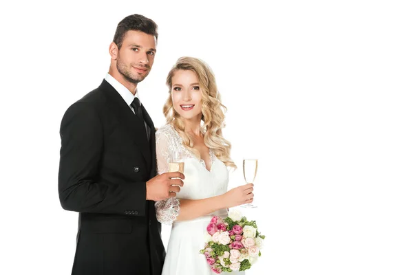 Happy young newlyweds with champagne glasses looking at camera isolated on white — Stock Photo