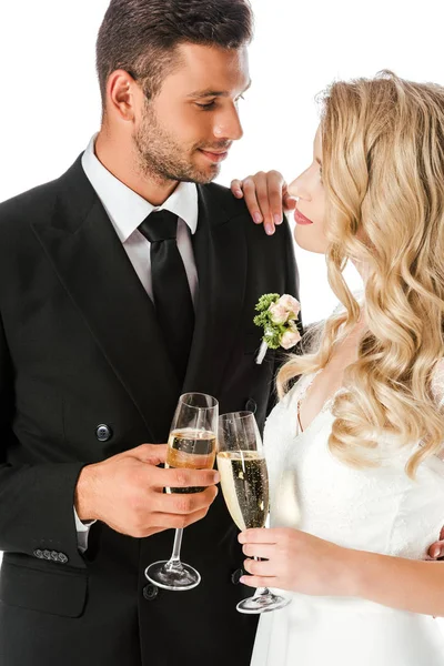 Hermosa novia joven y novio tintineo copas de champán aislado en blanco - foto de stock
