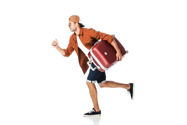 Vista laterale di bell'uomo che corre con bagagli isolati su bianco — Foto stock