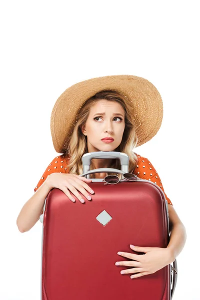 Asustada hermosa chica abrazando bolsa de viaje y mirando hacia arriba aislado en blanco - foto de stock
