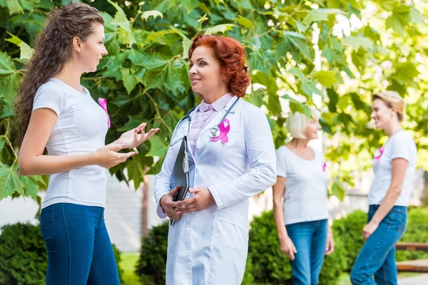 Жінка говорить зі усміхненим лікарем на відкритому повітрі, концепція обізнаності про рак молочної залози — стокове фото