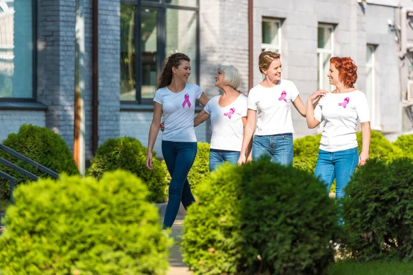 Happy women with breast cancer awareness ribbons walking together and smiling each other — Stock Photo