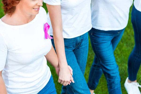 Tiro recortado de mulheres de mãos dadas e andando no gramado, conceito de consciência de câncer de mama — Fotografia de Stock