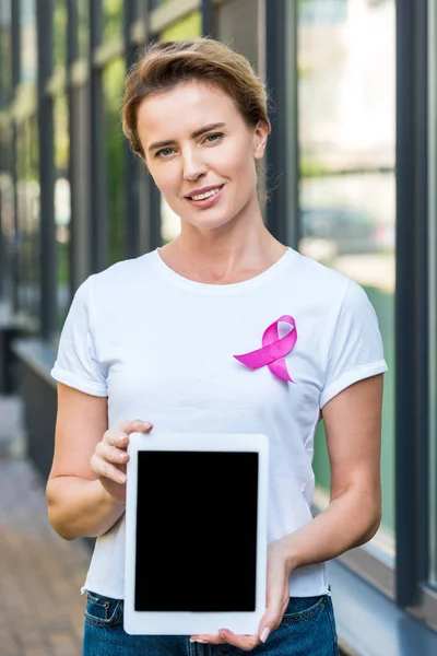 Femme avec ruban rose tenant tablette numérique et regardant la caméra, concept de sensibilisation au cancer du sein — Photo de stock
