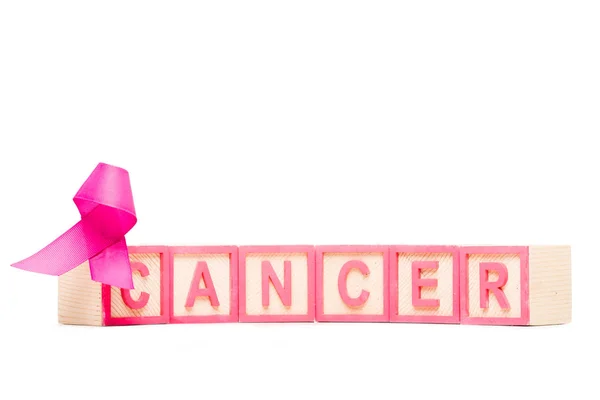 Close-up view of pink ribbon and cubes with word cancer isolated on white — Stock Photo