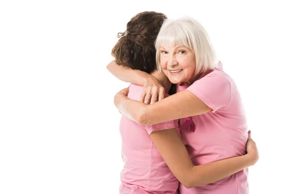 Young and senior women in pink t-shirts hugging isolated on white, breast cancer awareness concept — Stock Photo