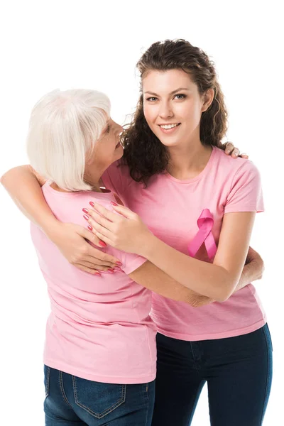 Smiling women in pink t-shirts hugging isolated on white, breast cancer awareness concept — Stock Photo