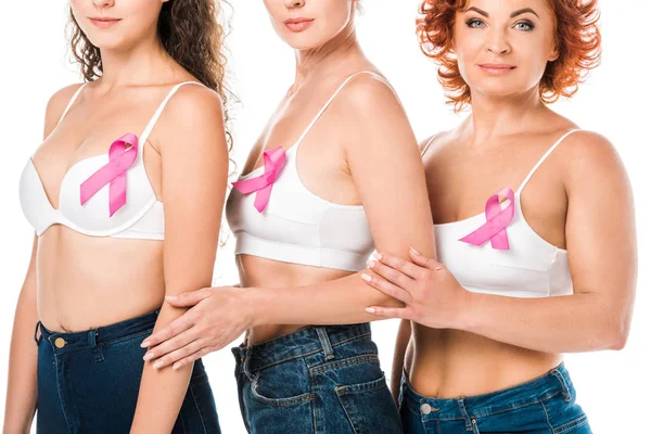 Обрізаний знімок жінок у бюстгальтерах з стрічками поінформованості про рак молочної залози, що стоять ізольовано на білому — стокове фото